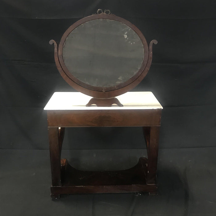Antique mahogany vanity with brass detailing, a white marble top, and an attached mirror 
