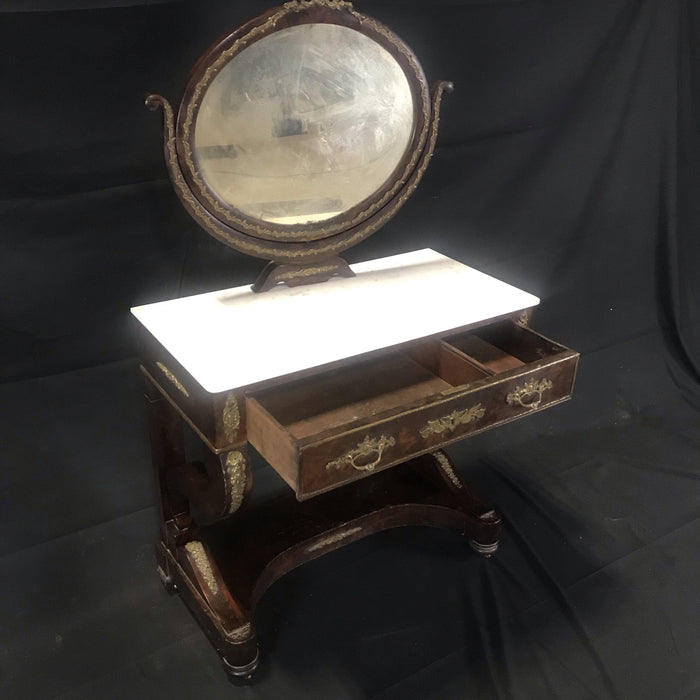 Antique mahogany vanity with brass detailing, a white marble top, and an attached mirror 
