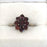 Vintage engagement ring of garnet stones in a flower design on a gold band 