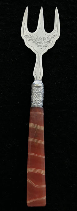 Antique silver bread fork with a brown and red handle