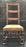 Antique ladder back chair with turned legs and brown upholstered seat 