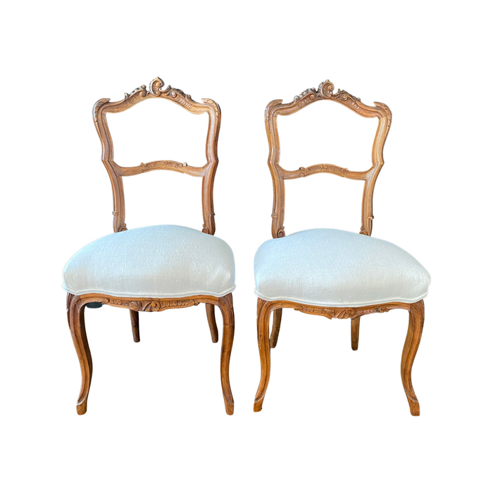 Antique pair of carved wooden side chairs with upholstered seat cushions 