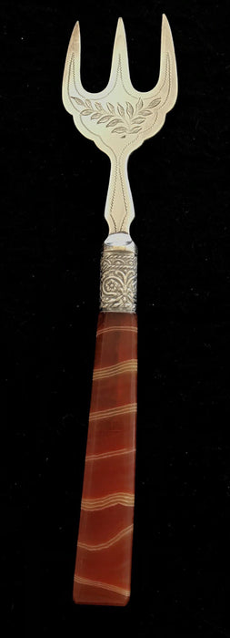 Antique silver bread fork with a brown and red handle